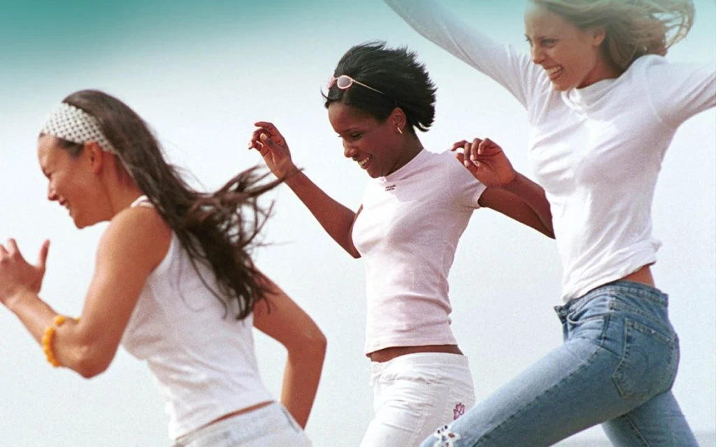 Three women running and jumping outdoors together